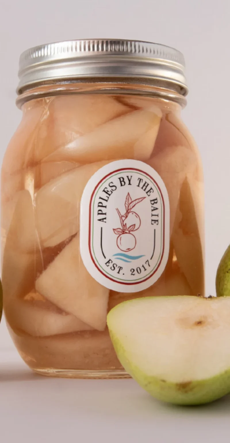 Jar of preserved pear chunks with fresh pears